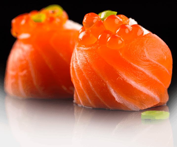 Duas peças de sushi feitas com fatias de salmão fresco, cobertas com ovas de salmão laranja e guarnecidas com cebolinha verde, são exibidas em uma superfície preta brilhante.