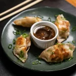 dumplings-com-molho-em-um-prato-verde